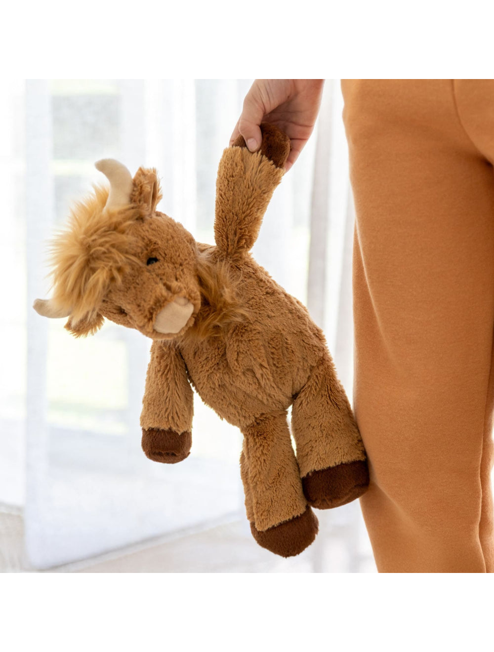 Person holding a plush toy in front of a white curtain