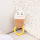 Plush ice cream cone toy with a teething ring on a soft surface