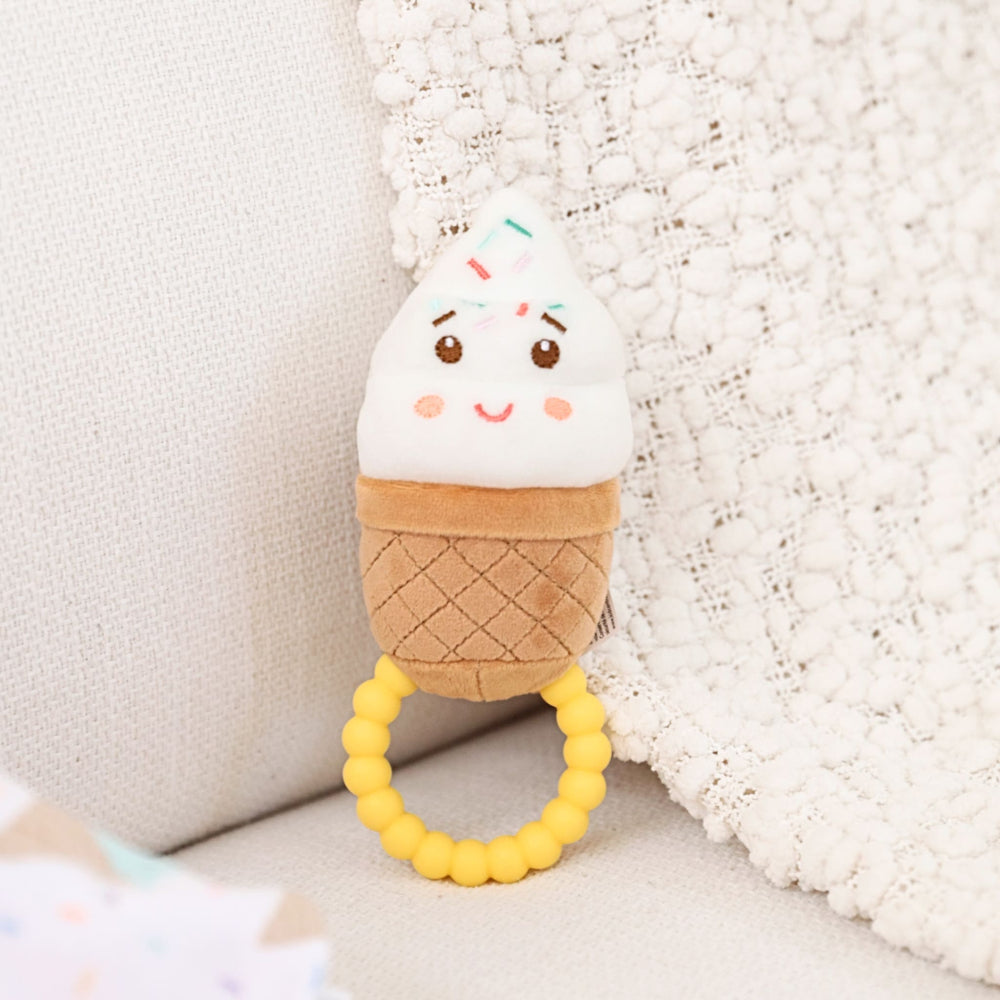 Plush ice cream cone toy with a teething ring on a soft surface