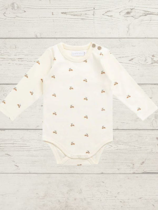 White baby bodysuit with gold patterns on a light wooden surface