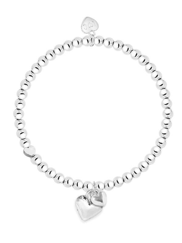 Silver beaded bracelet with a heart charm on a white background