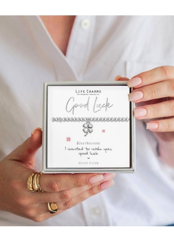 Person holding a box of Life Charms with a bracelet labeled 'Good Luck'.