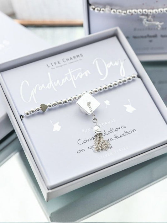 Graduation-themed bracelet with charm in a gift box on a light background
