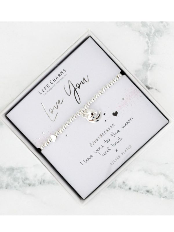 Silver bracelet with engraved message on a white card, placed on a marble surface.