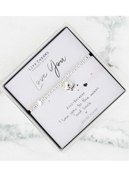 Silver bracelet with engraved message on a white card, placed on a marble surface.