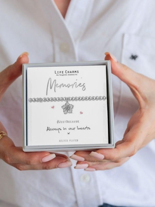 Jewelry box with 'Life Charms' branding held by hands against a white background