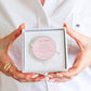 Rose Quartz crystal in a box held by hands against a white background
