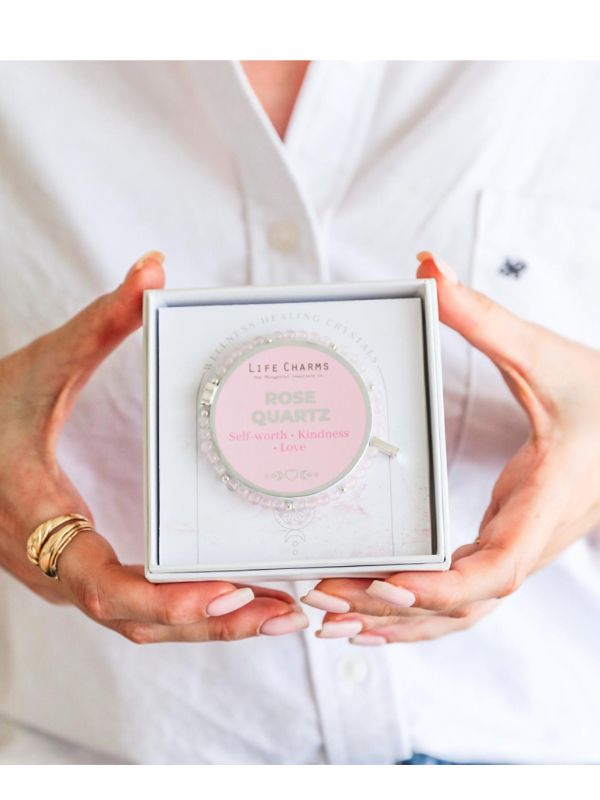 Rose Quartz crystal in a box held by hands against a white background