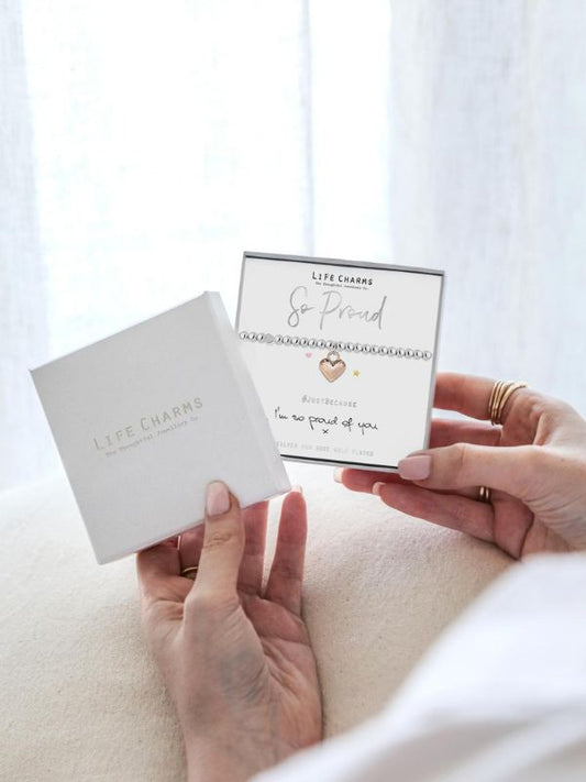 Two hands holding a card and a small box with 'Life Charms' branding.