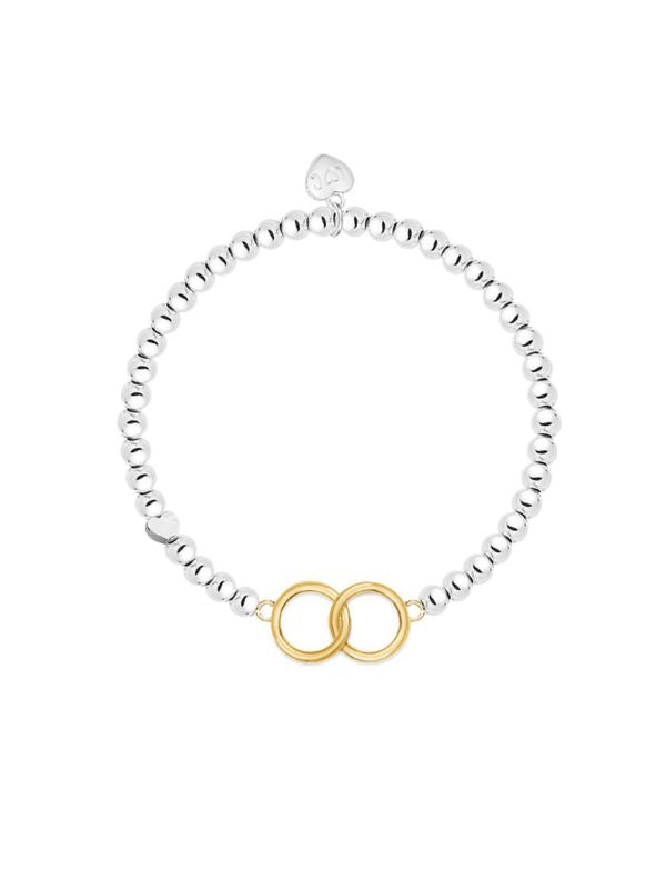 Silver bracelet with a gold interlocking circle charm on a white background