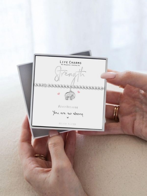 Person holding a card with 'Strength' message and Life Charms branding.