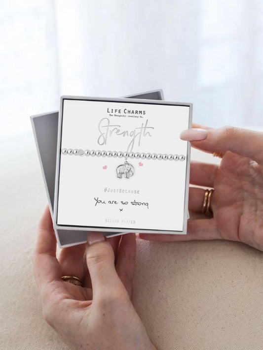 Person holding a card with 'Strength' message and Life Charms branding.