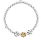 Pearl bracelet with gold and silver floral charms on a white background