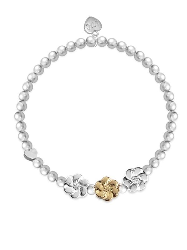 Pearl bracelet with gold and silver floral charms on a white background