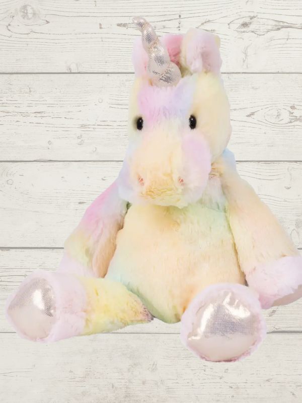 A multicolored plush toy resembling a unicorn with a white body, pink ears and tail, and yellow and green accents on a wooden background.