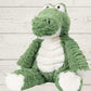 A plush toy resembling a green marshmallow with a crocodile-like face, made from soft fabric, designed for cuddling and play.