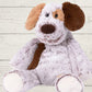 A plush toy resembling a marshmallow puppy with embroidered details, soft fabric, and a stuffed design, placed against a wooden background.
