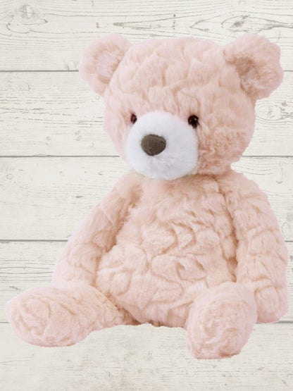 Pink teddy bear on a light wooden background