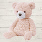 Pink teddy bear on a light wooden surface