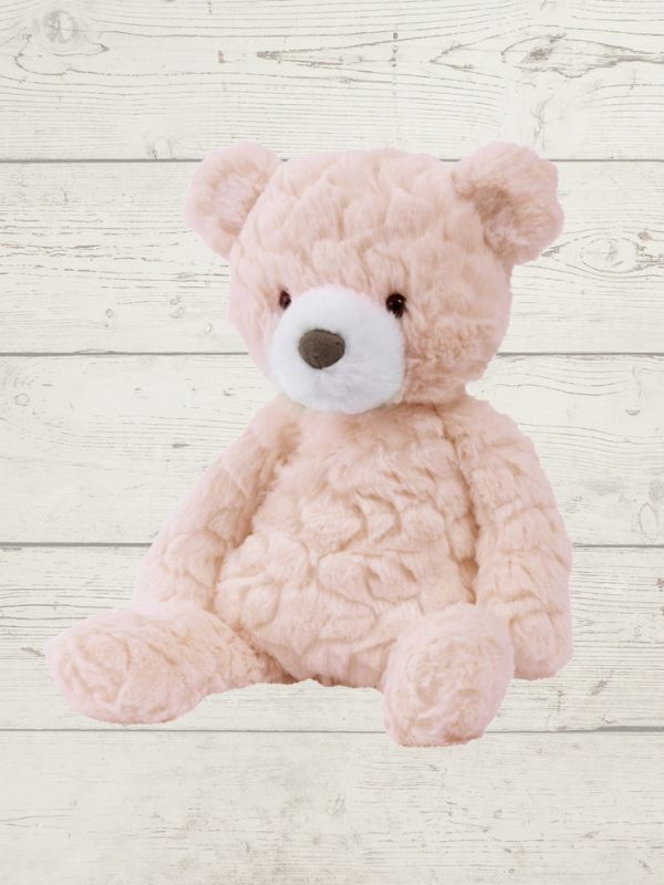 Pink teddy bear on a light wooden surface