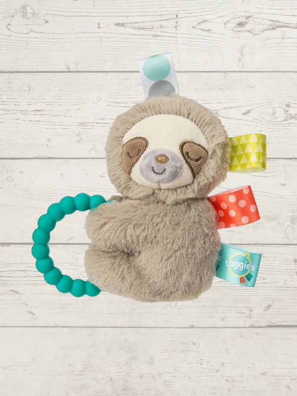 Plush sloth toy with teething ring on a wooden surface