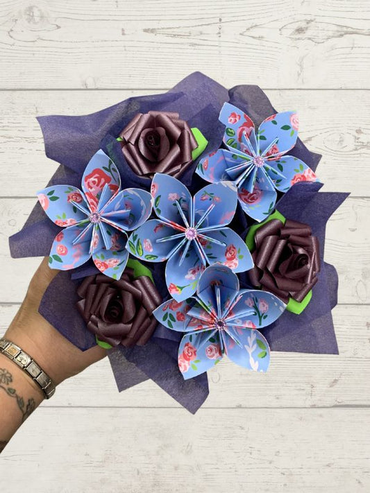 Bouquet of paper flowers with blue and brown colors on a wooden surface