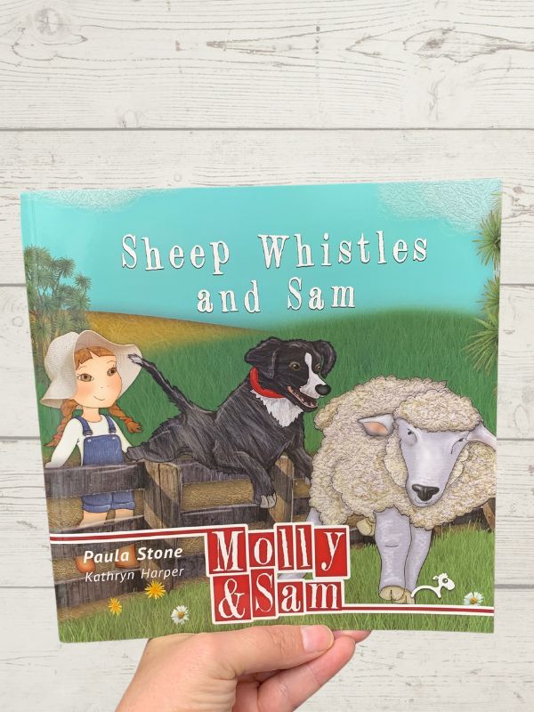 book with a little girl, sheep and dog on cover on a wooden background