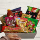 A gift box filled with various snack food items including chocolates, chips, and biscuits.