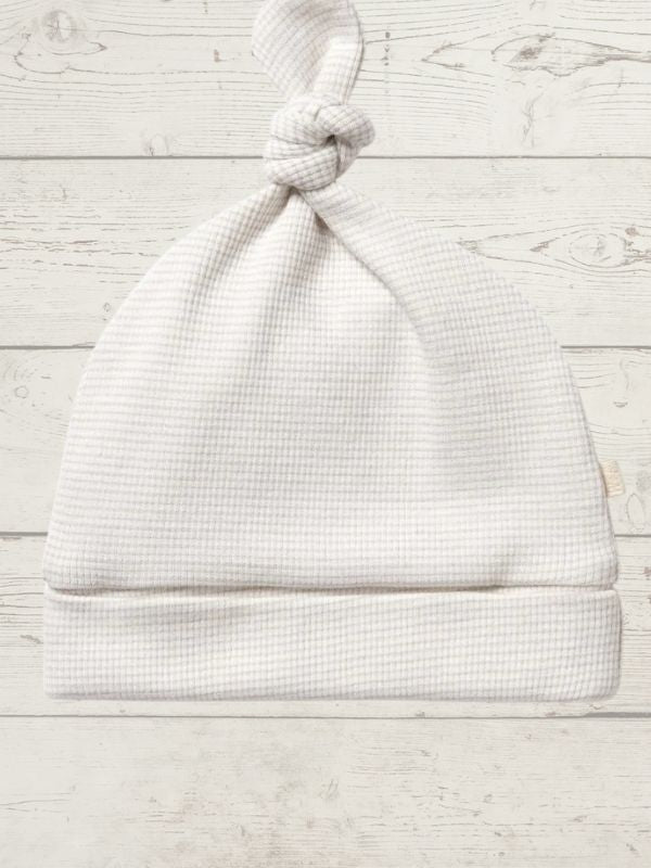 White baby hat on a light wooden surface