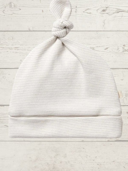 White baby hat on a light wooden surface