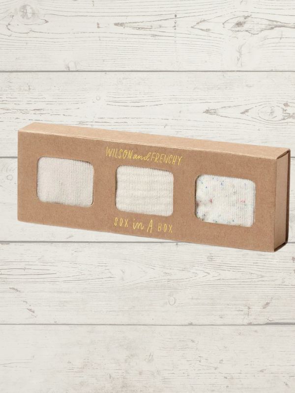Kraft paper box with three pairs of socks on a wooden surface, featuring 'Wilson and Frenchy' branding.