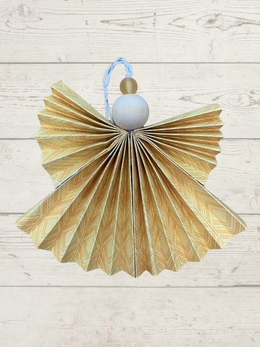 Decorative angel made from folded paper with a blue ribbon on a light wooden background