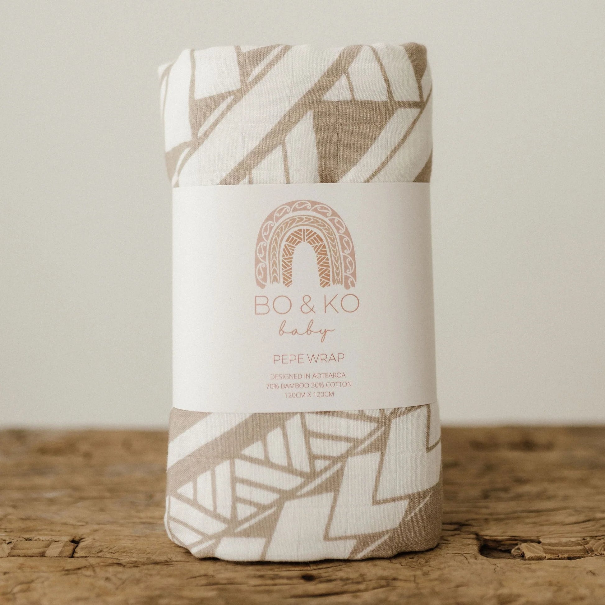 Baby swaddle wrap with geometric pattern in packaging on a wooden surface