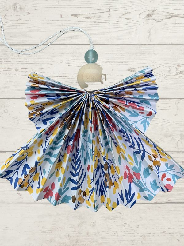 Colorful floral-patterned dress on a wooden hanger against a light wooden background
