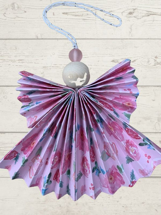 Decorative item with floral pattern, white bead, and pink string on a light wooden background