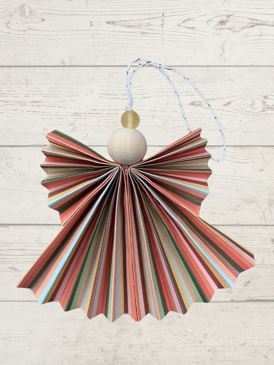 Decorative hanging item made from colorful paper with a wooden bead on a light wooden background
