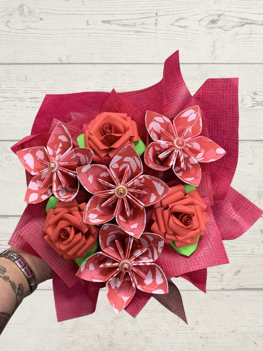 Bouquet of red and pink flowers with a pink ribbon on a light wooden surface