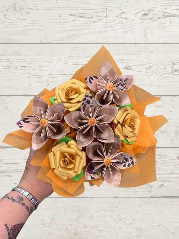 Posy box of paper flowers in yellow, orange, and brown on a wooden surface