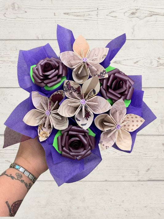 Bouquet of paper flowers in purple and beige on a wooden surface