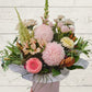 pastel flowers arranged into a container with pastel wrap. 