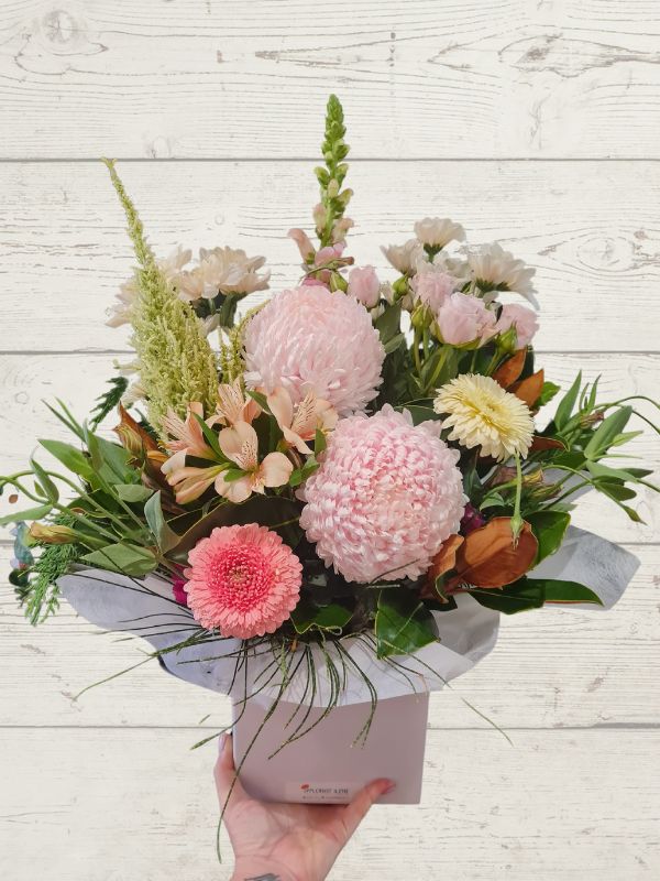 pastel flowers arranged into a container with pastel wrap. 