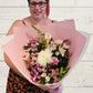 Person holding a pink and white bouquet with pink wrap. 