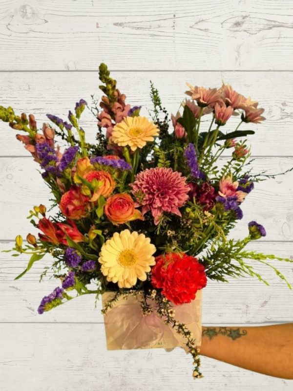 arrangement of pastel coloured flowers with a white box and white ribbon. 