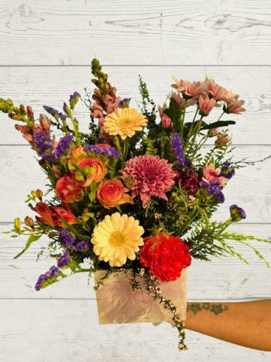 arrangement of pastel coloured flowers with a white box and white ribbon. 