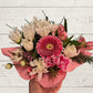 Bouquet of flowers held by a hand on a light wooden surface