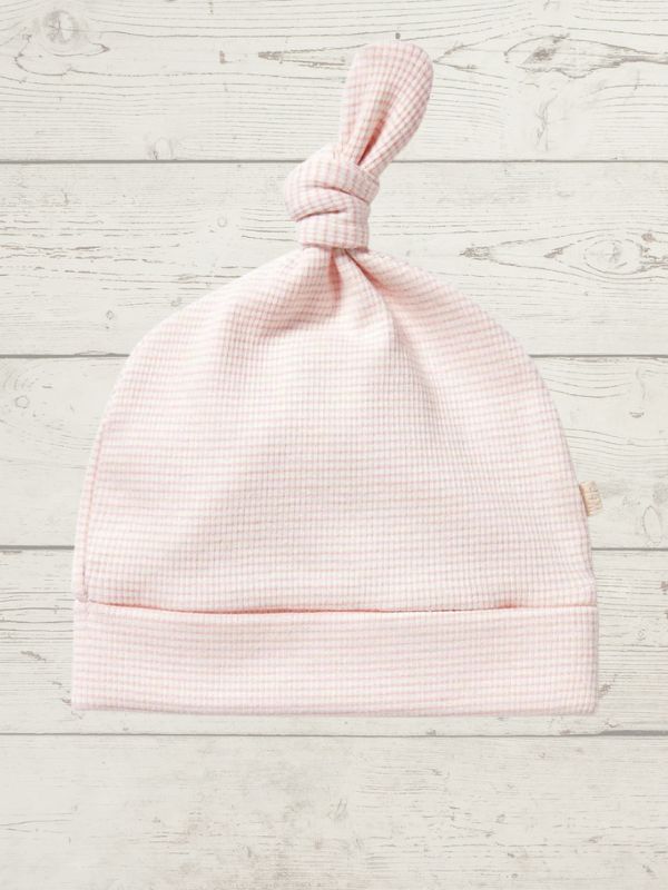 Pink baby hat on a light wooden surface
