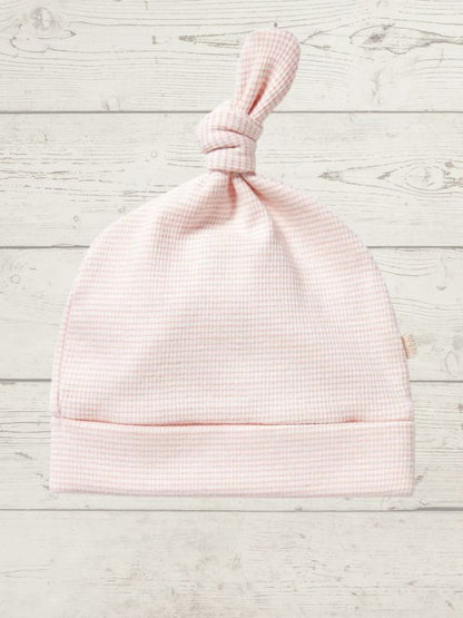 Pink baby hat on a light wooden surface