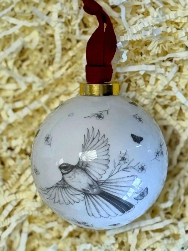 fantail in flight on a white bauble on a brown background