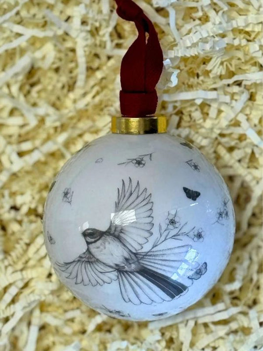 fantail in flight on a white bauble on a brown background