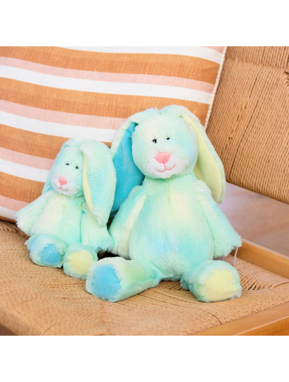 Colorful plush bunny sitting on a striped cushion